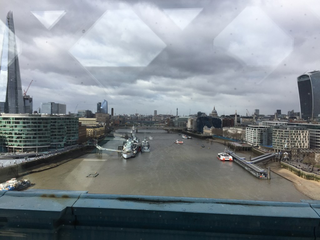View along the River Thames from the upper walkway of Tower Bridge, with the Shard on the left and the Walkie Talkie building on the right. In the distance St Paul's Cathedral and the BT Tower are visible.