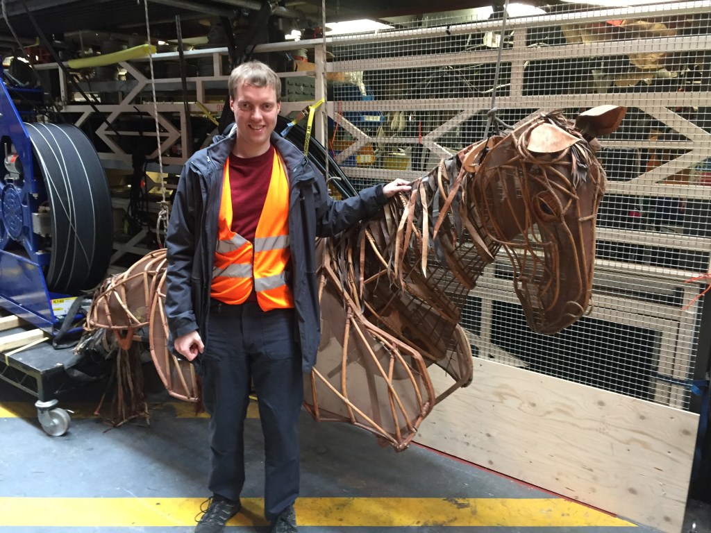 Glen standing with a large wooden frame horse model used in War Horse.
