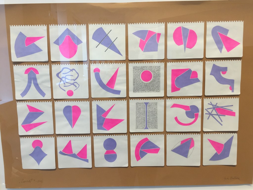 A grid of 24 artworks on a board, 6 across and 4 down. Each drawing is on a small square piece of paper, with square, turret-like edging at the top that shows it was removed from a notebook. The drawings use a mixture of pink and purple shapes, usually one of each connected in some way, but there are other variations too.