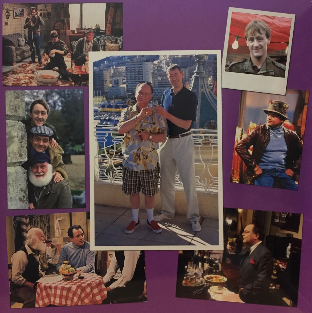 Collage of photos from Only Fools And Horses, featuring Del Boy, Rodney, Grandad and Uncle Albert. A large photo in the centre shows Del Boy and Rodney smiling and clinking glasses of champagne, as they stand on a balcony in the sunshine with a cityscape behind them.