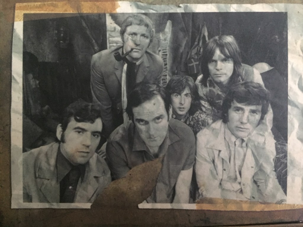 Black and white photo of the Monty Python team on the box of the Blu-ray box set. At the back are Graham Chapman, Eric Idle and Terry Gilliam, while in front of them are Terry Jones, John Cleese and Michael Palin.