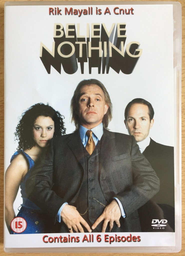 DVD cover for Believe Nothing, with the tagline Rik Mayall Is A Cnut. The cover photo shows Professors Adolphis Cnut, Doctor Hannah Awkward and Brian Albumen.
