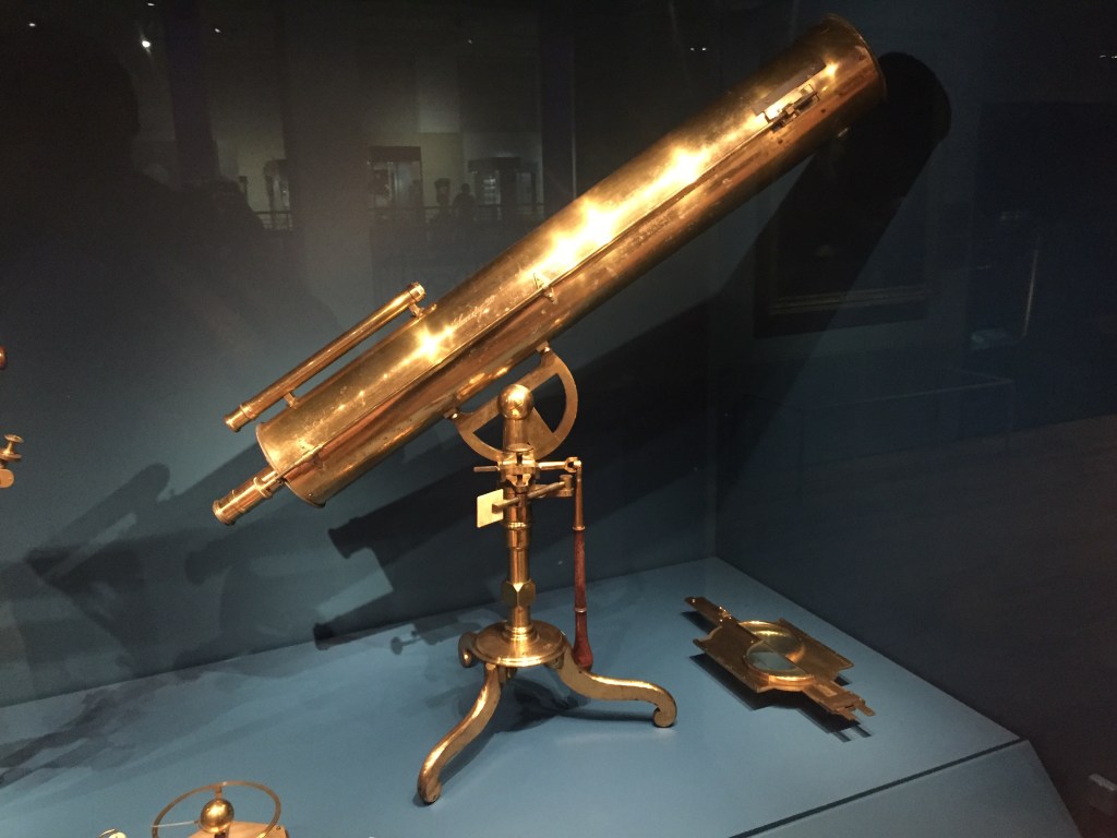 A small telescope on a tripod, finished in polished brass.