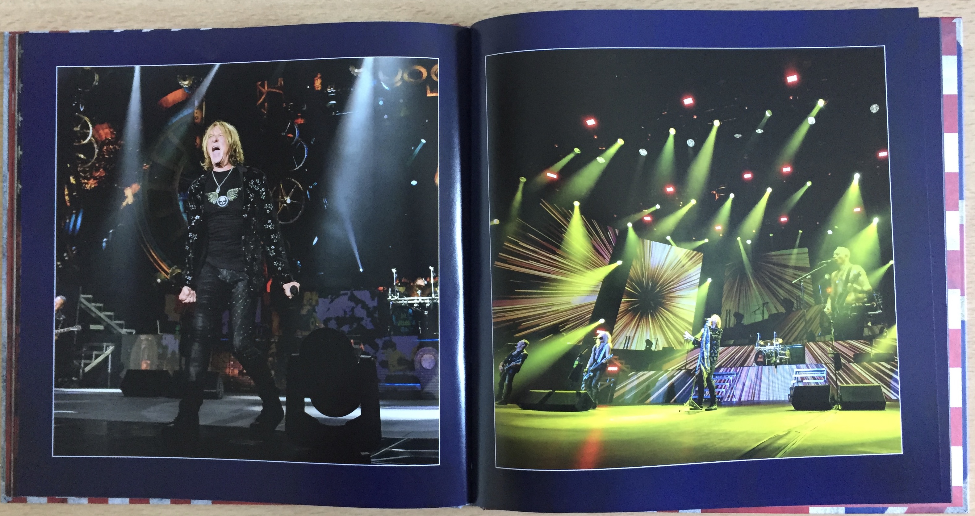 2 page spread from the book of photos in the Def Leppard London To Vegas box set. The left page shows singer Joe Elliot, dressed mainly in black, fists clenched by his side and mouth open wide as he sings powerfully. The right page shows a few of the entire band performing under a set of many green spotlights that are pointing in all directions to cover the stage.