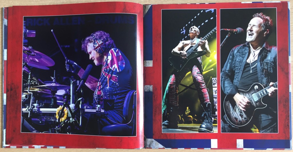 2 page spread from the book of photos in the Def Leppard London To Vegas box set. The left page shows one-armed drummer Rick Allen performing, wearing Union Jack emblazoned headphones, and a Union Jack patch over the unused arm hole of his jacket. The right hand page shows guitarists Vivian Campbell and Phil Collen performing, Vivian singing as he plays while Phil performs topless.