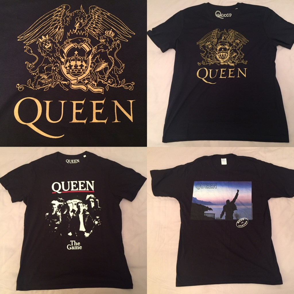 3 Queen t-shirts. One is dark blue with the Queen crest in large gold print, with the crest featuring a phoenix, lions and fairies. One is black, with a black and white image of the band posing together on the album cover for The Game. And one is black with a colour image of the Made In Heaven album cover, showing Freddie Mercury's statue looking out over a scenic sea view.