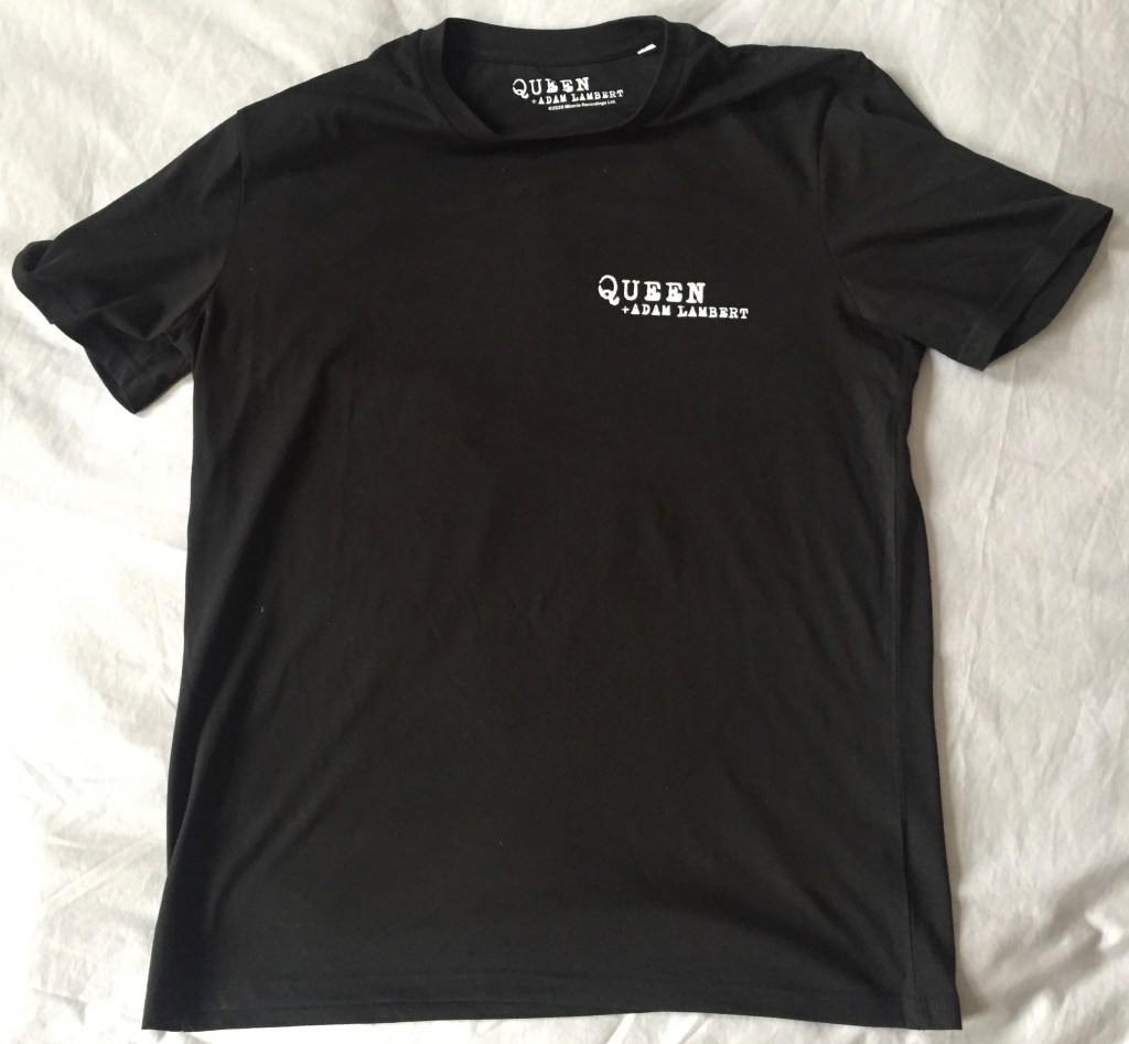 The rear side of the black t-shirt, featuring a small version of the Queen & Adam Lambert logo in white in the top right.