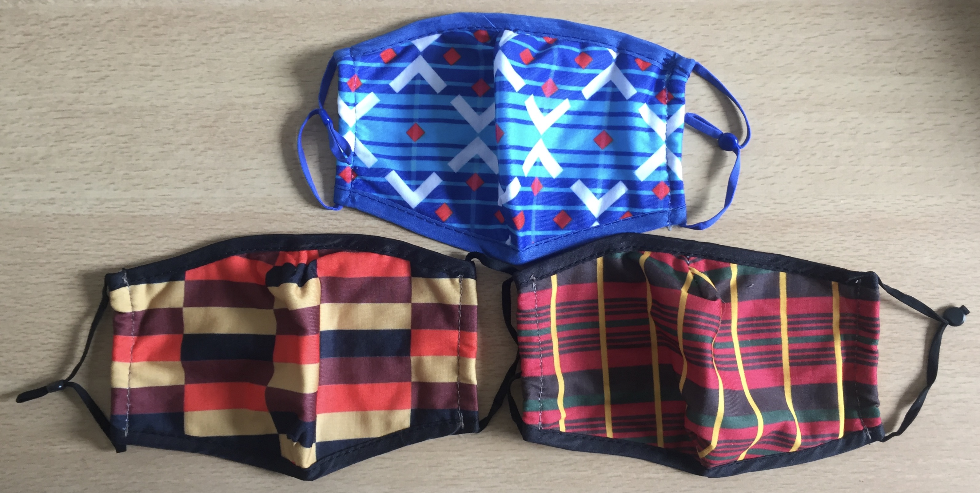 3 face masks, featuring colourful moquette designs from Routemaster buses, Victoria Line trains and District Line trains. They feature a variety of lines, stripes, blocks and diamond shapes to form their distinctive looks, with one mask predominantly blue and white, while the other 2 have a mixture of black, red, orange and yellow colours.