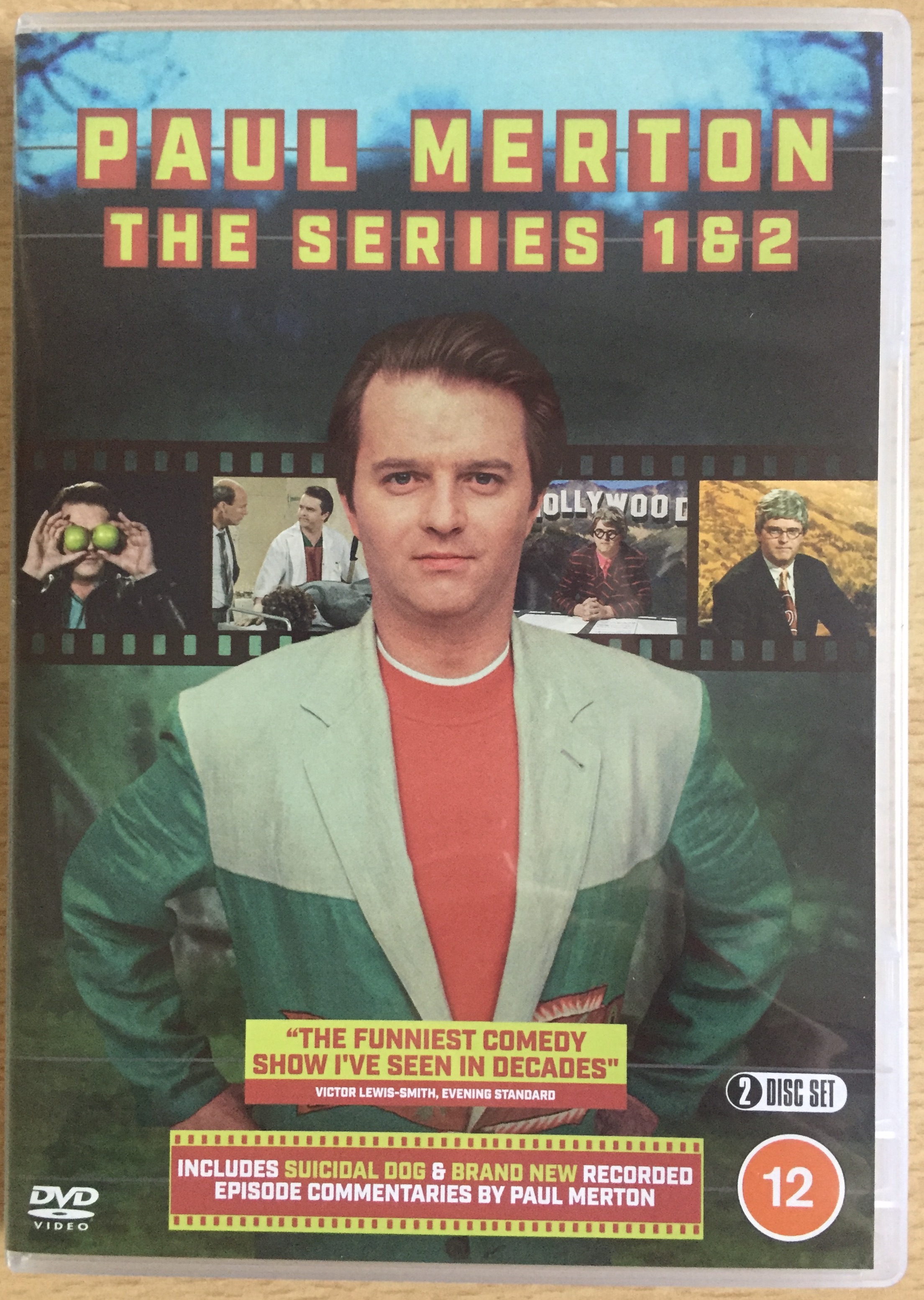 Front cover of the DVD for Paul Merton The Series, showing an image of him standing with his hands on his hips, with a film reel behind him showing images from the programme. The DVD is rated 12 and includes his short film Suicidal Dog and brand new audio commentaries by Paul.