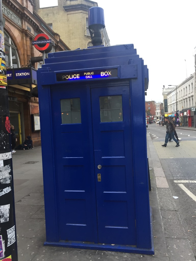 Tall blue police call box, very similar to Doctor Who's Tardis, on the pavement outside Earl's Court Underground Station.