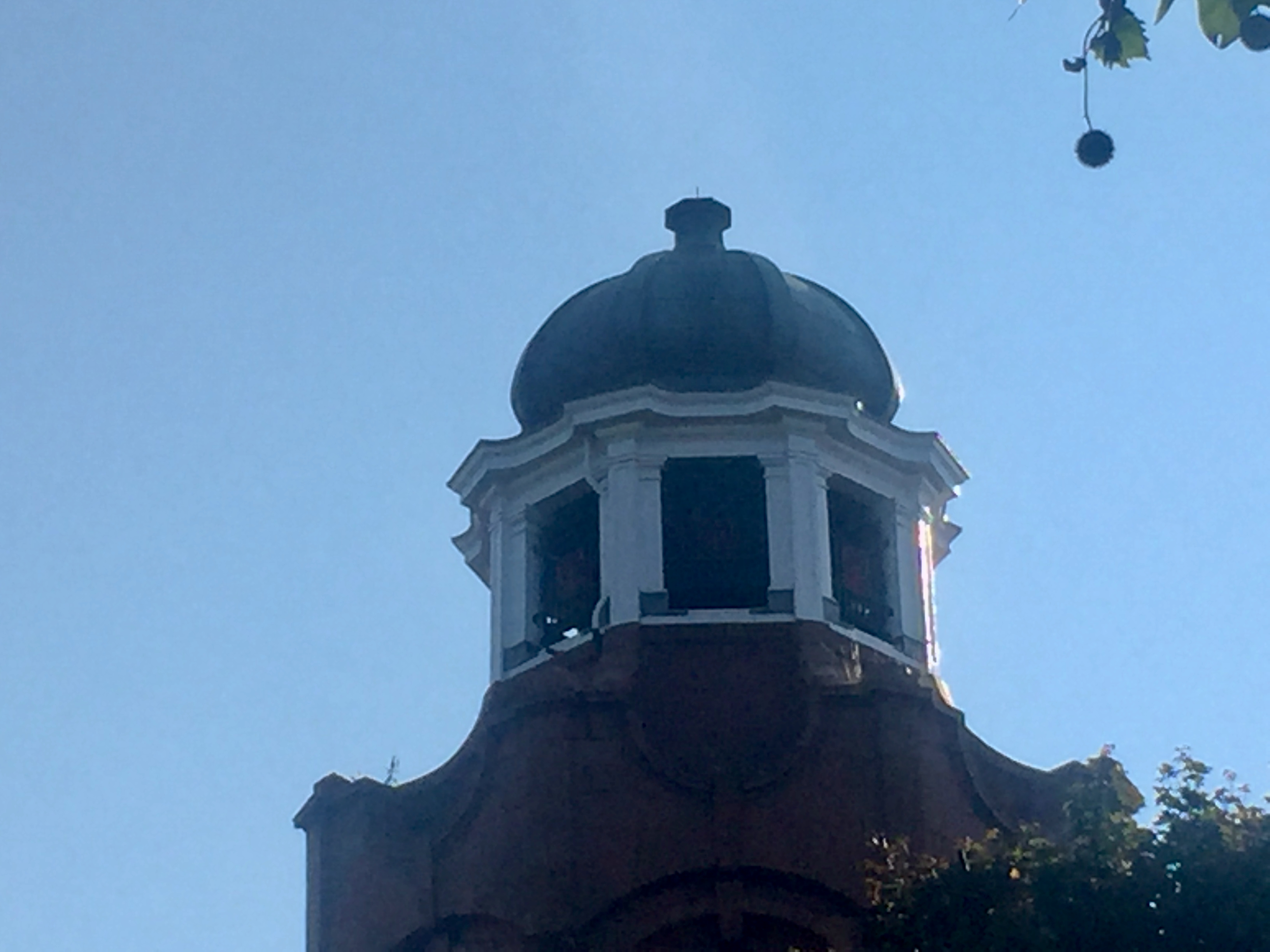 The top of the tower on the Shepherd's Bush Empire. A hexagonal section in white has a window on each of its 6 sides, and this is topped by a dark coloured dome.