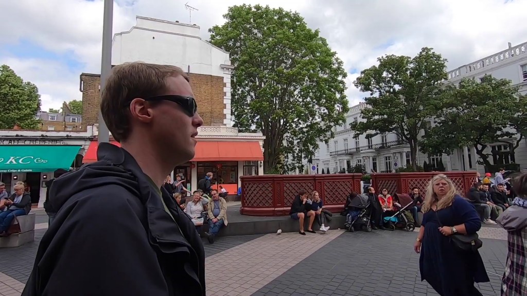 Glen wearing sunglasses as he walks down a busy street.