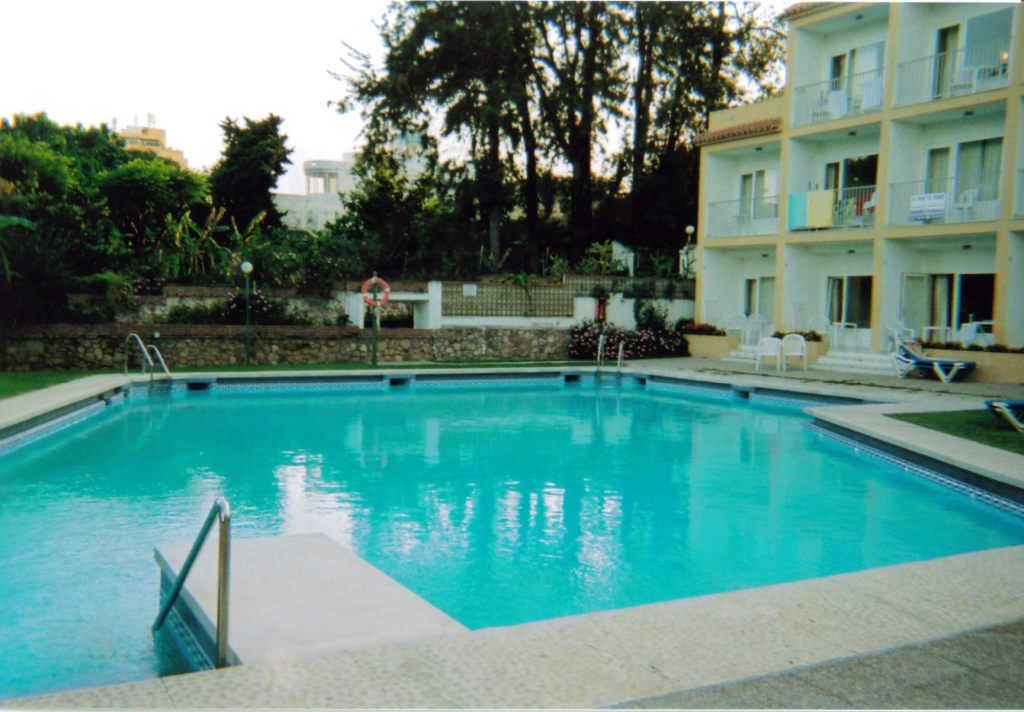 Another swimming pool at Carihuela Park Palace, with an apartment block on one side, and trees on another.