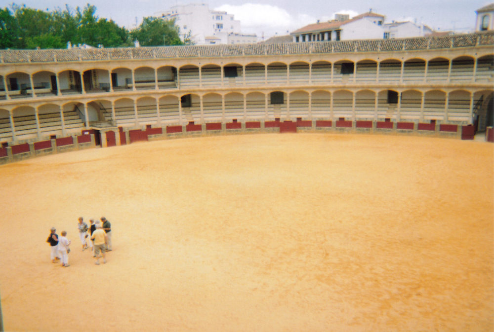 Large round bullring in Ronda, with arches in front of the 2 floors of seating all around the edge.