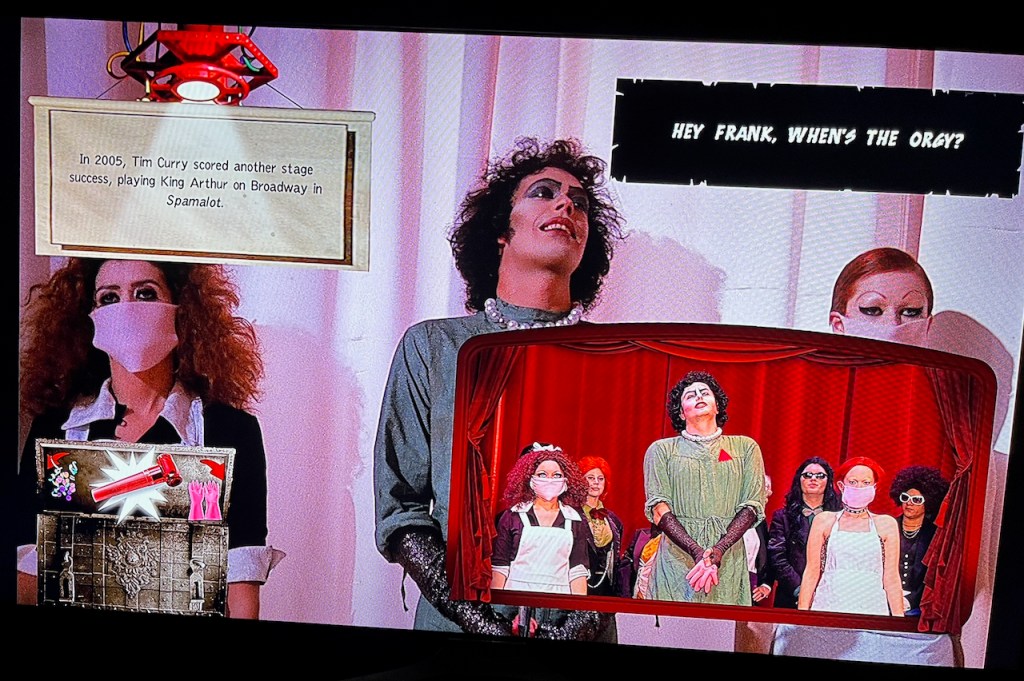 Screengrab from the Midnight Experience on the Rocky Horror Blu-ray. As Frank N Furter stands with his 2 assistants, 4 items are overlaid over the top. There's trivia about actor Tim Curry, an audience callback saying Hey Frank where's the orgy?, a box of props, and a shadow cast who are copying the film on a stage.