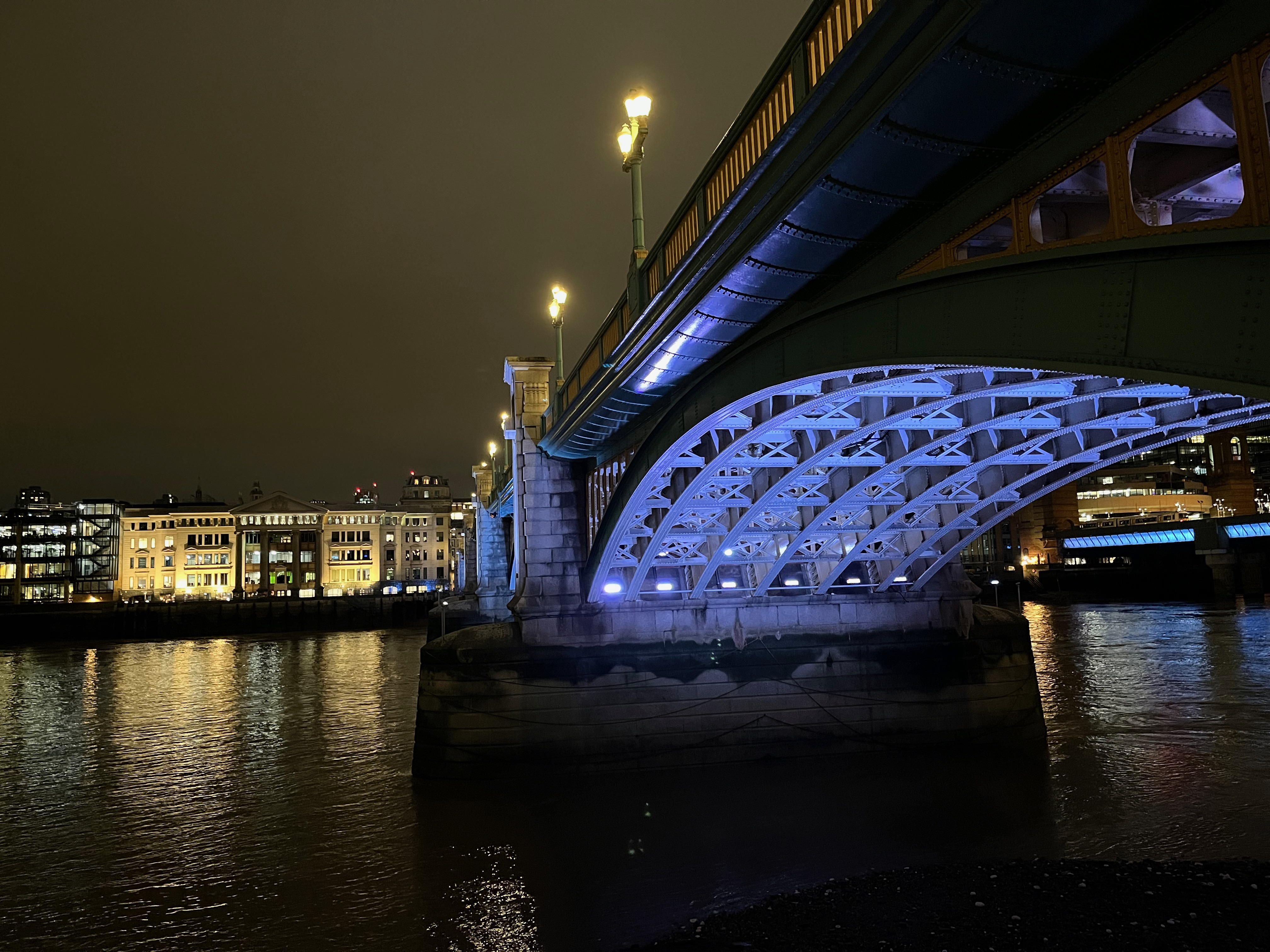 Close-up of an archway under Southwark Bridge, bathed in blue light.