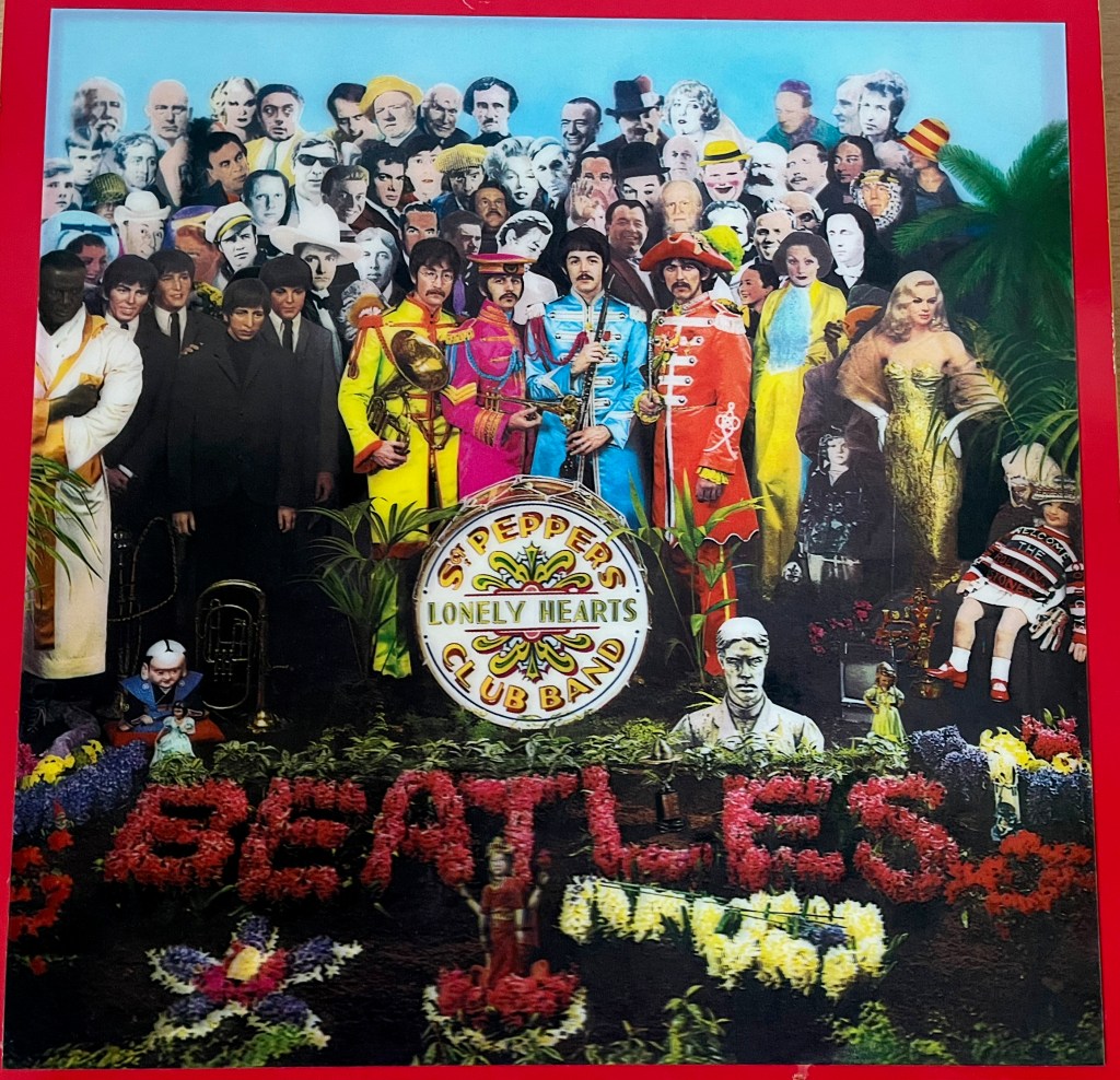 Front cover for the Sergeant Pepper box set, featuring a large version of the album cover. The 4 band members, dressed in yellow, pink, blue and red respectively, stand in front of a drum with the album title on it, and below that the word Beatles is spelled out using colourful flowers. Behind the band is a huge crowd of famous figures, including Mae West, Fred Astaire, Bob Dylan, Tony Curtis, Laurel & Hardy, HG Wells, Oscar Wilde, Lewis Carroll, Shirley Temple and Albert Einstein, to name just a few.