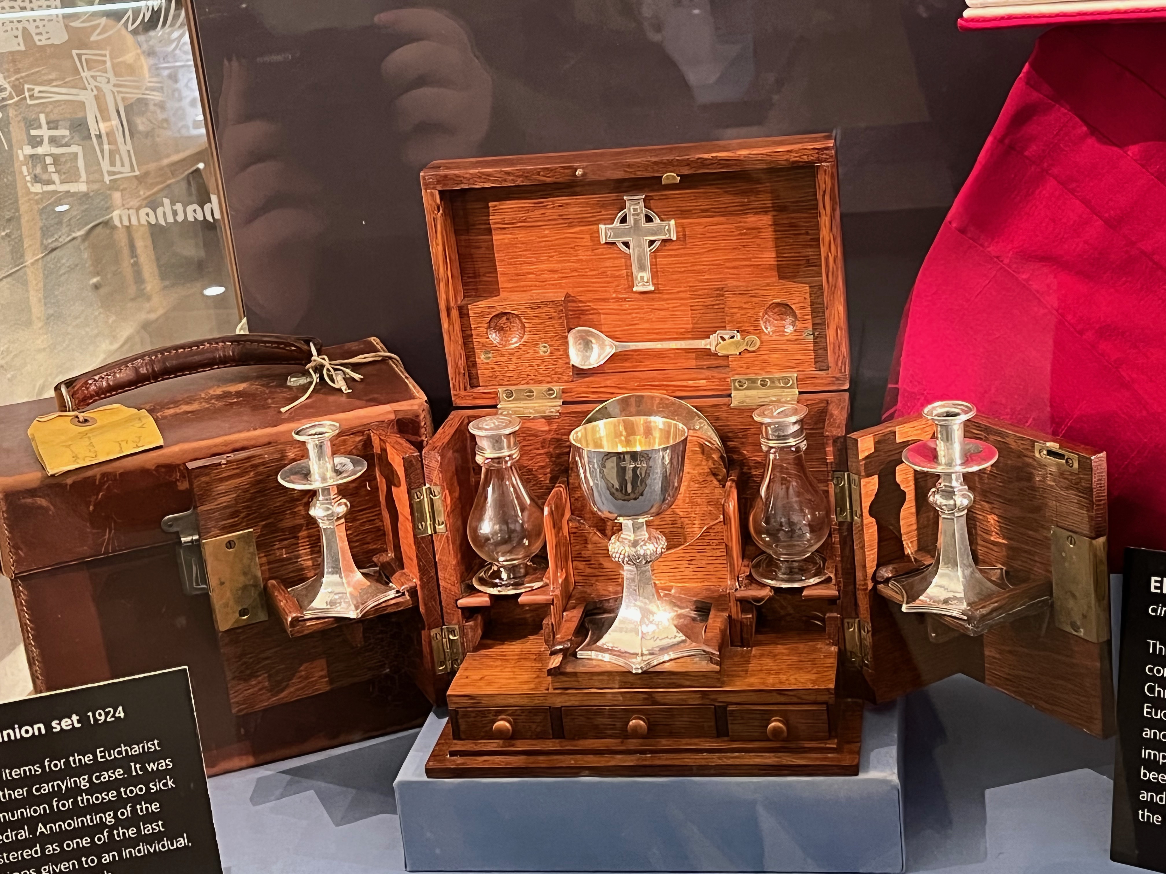 Portable communion set including a small cup, glass vials, a candle holder and a cross, inside a carrying case.