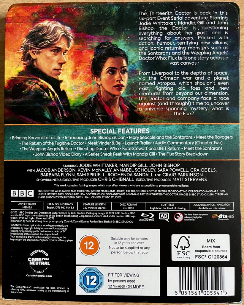 Back cover sleeve of the Doctor Who Series 13 Blu-ray steelbook, showing a description of the series and the list of extra features, alongside an image of companions Dan and Yaz.
