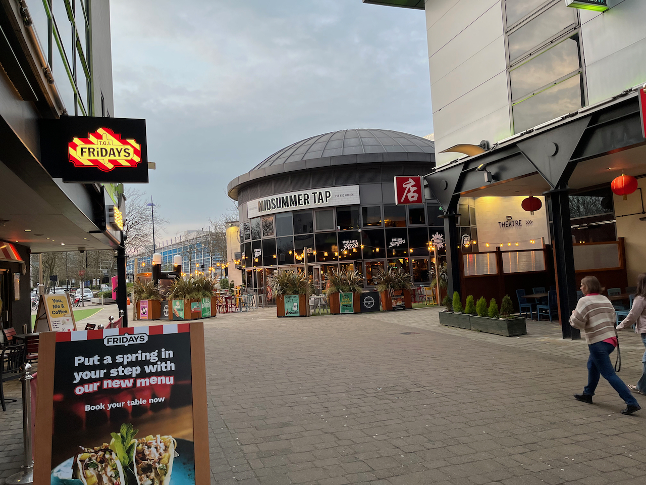 View down a street towards the Midsummer Tap pub, with a branch of TGI Fridays on the left.