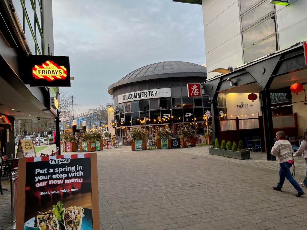 View down a street towards the Midsummer Tap pub, with a branch of TGI Fridays on the left.