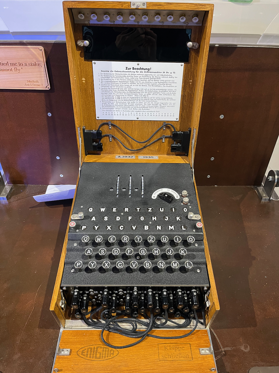 German Enigma machine, effectively a typewriter in a wooden box, but with additional rotor wheels and light-up letters on the top, and a collection of sockets on the front panel with wires sticking out.