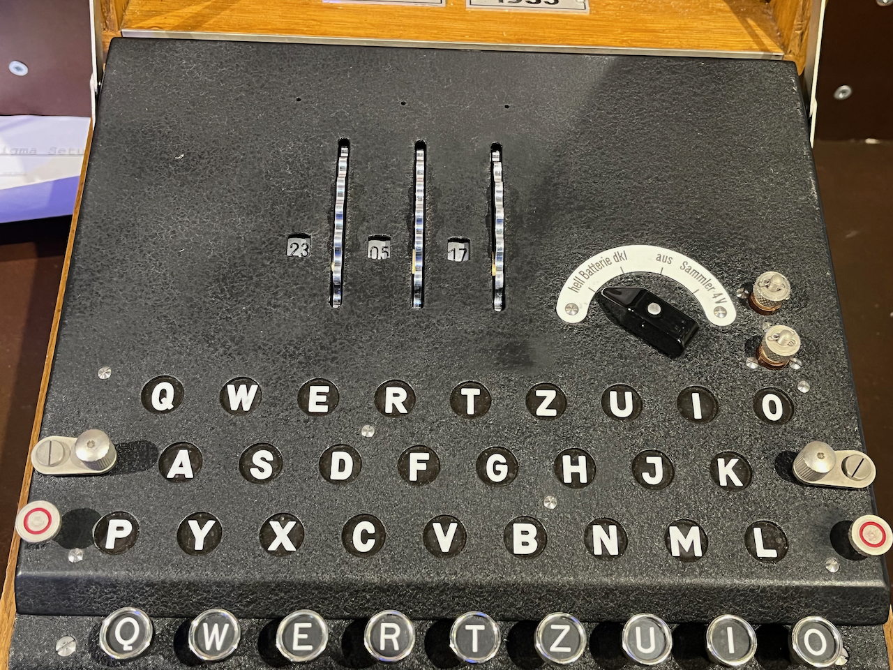 Close-up of the top of the Enigma machine, showing 3 embedded rotor wheels, with a tiny window next to each showing the current number it's been set to.