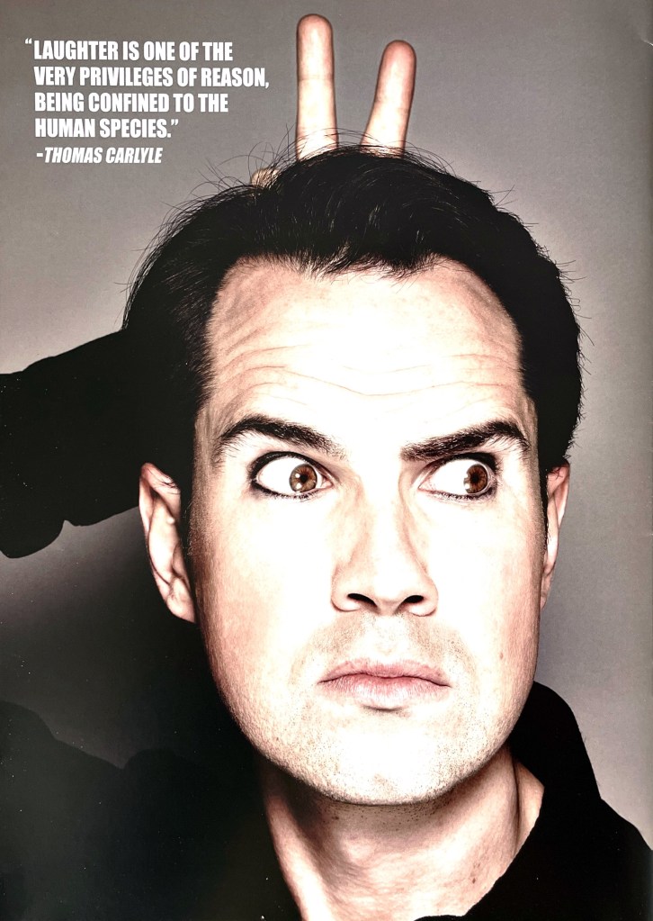 A photo of Jimmy Carr's face, with 2 fingers poking up behind it like devil horns. Next to the image is a quote from Thomas Carlyle that says Laughter is one of the very privileges of reason, being confined to the human species.
