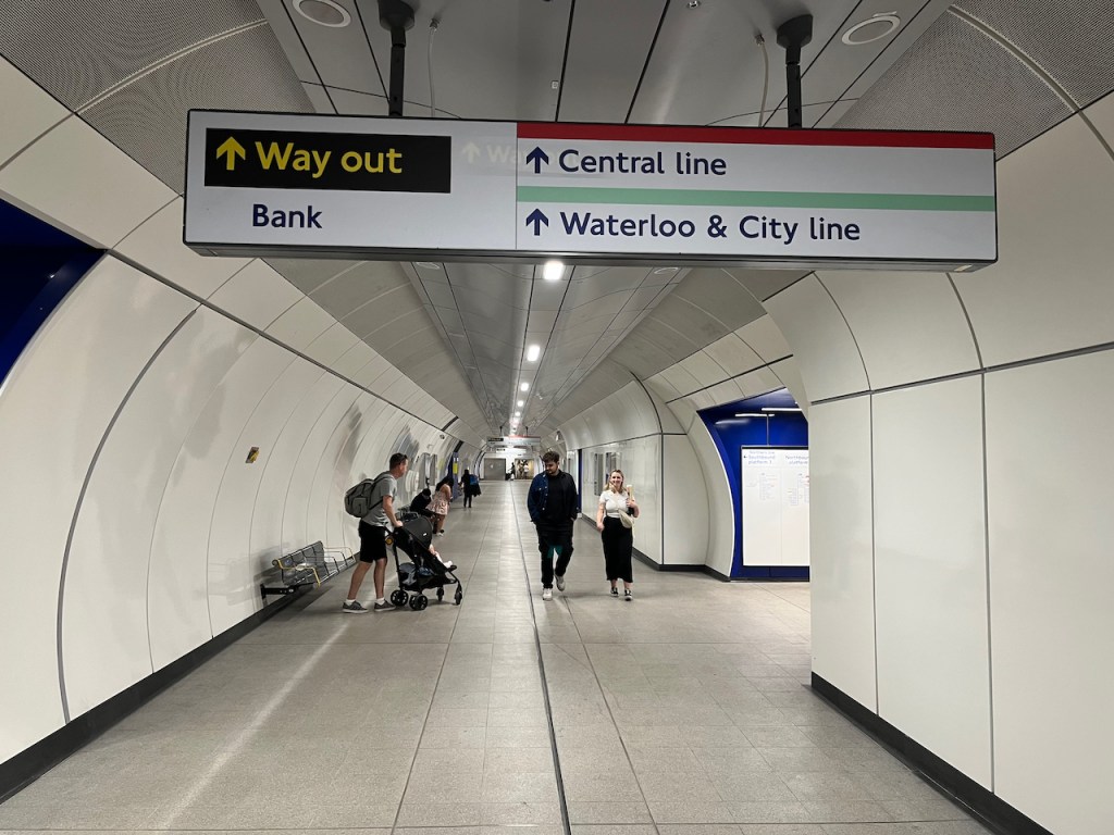 The new wide concourse for the Northern Line at Bank, formed from the old Southbound tunnel. The walls and floors are white, while the side tunnels to each platform have dark blue walls.