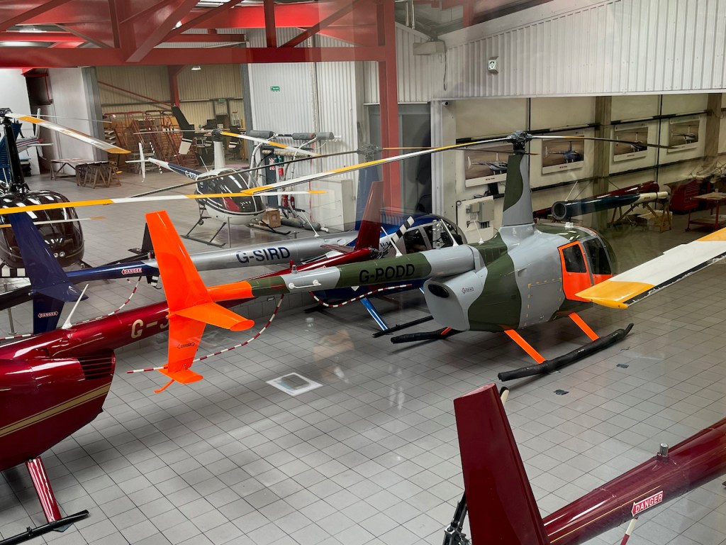 Helicopters in the Heli Air hangar owned by celebrities. David Jason's vehicle has blue and silver bodywork, while Jamiroquai's machine has green and silver bodywork, but with bright orange for the tail, front passenger section and legs.
