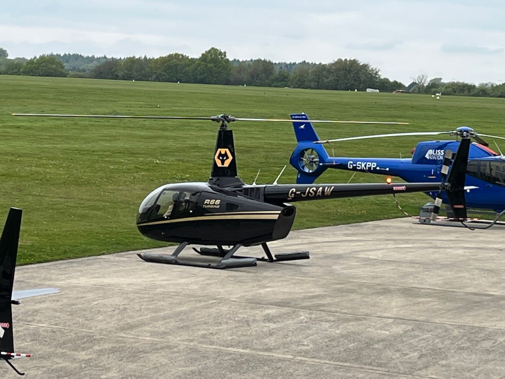 A black helicopter with a gold stripe along the side, and gold lettering that says R66 Turbine.