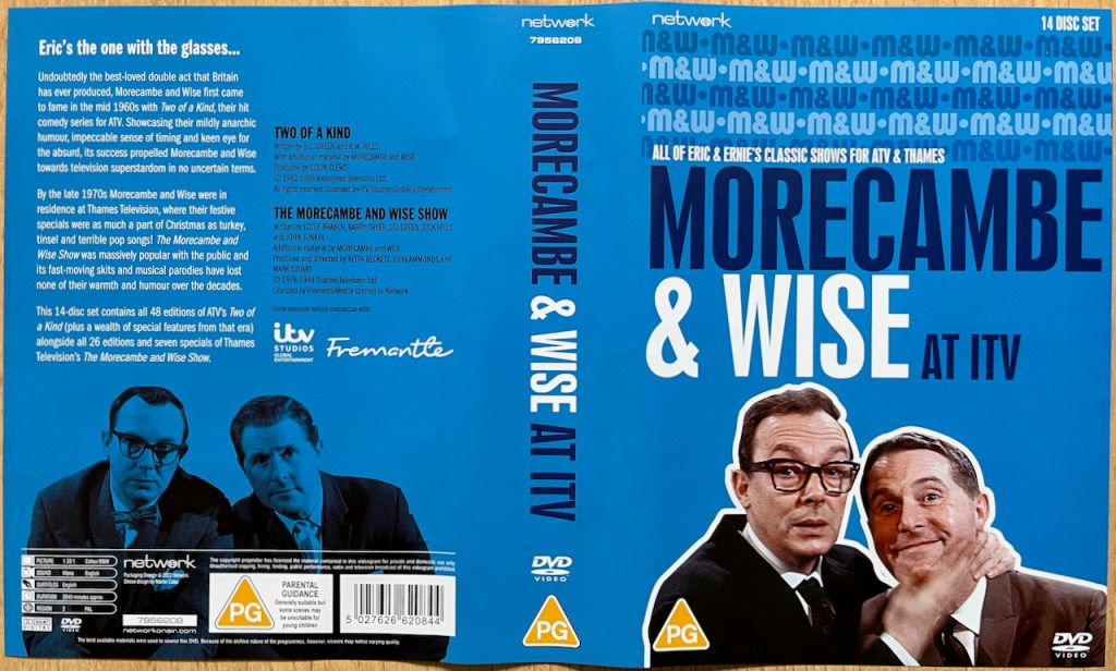 Outer cover spread for the Morecambe & Wise At ITV DVD set. The cover is blue, with a colour image of the duo on the front below the title of the set. Another image of the duo appears on the back cover, below the text about the contents of set, but tinted blue this time.
