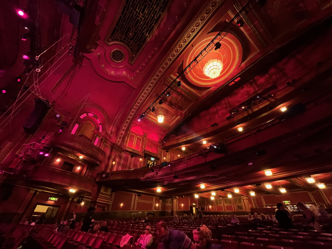 The auditorium of the Dominion Theatre, the walls bathed in red lighting.