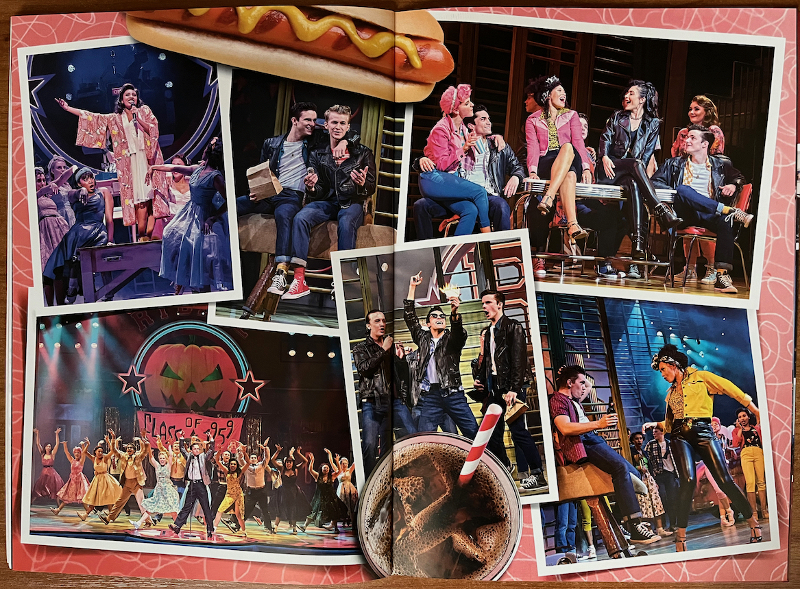 2-page spread from the programme for Grease The Musical, with a collage of images from different scenes in the show. One shows the whole cast standing with legs apart and hands in the air, in front of a backdrop that has an image of a carved Halloween pumpkin and a banner reading Class of 1959. Other photos show the boys and girls hanging out and singing or talking with their respective gang members.