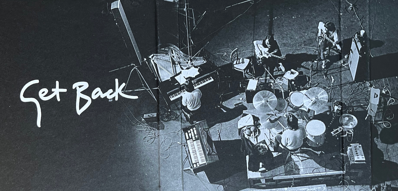 An overhead photo of The Beatles playing together in the studio, alongside the title Get Back in large white hand-written letters, from the inside of their Get Back Blu-ray set.