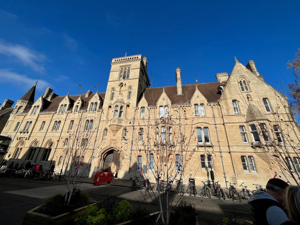 The large building of Balliol College. The building is mainly 3 storeys high with a sloping roof, apart from 4 storeys at each end, again with sloping roofs, and a 5 storey square tower in the centre.
