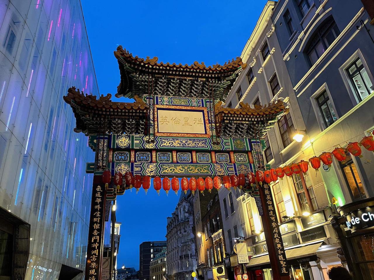 The Chinatown Gate, an ornate structure supported on 2 tall red pillars, decorated with traditional Chinese text and imagery. According to Apple's translation, the text on the white panel in the centre means England is auspicious.