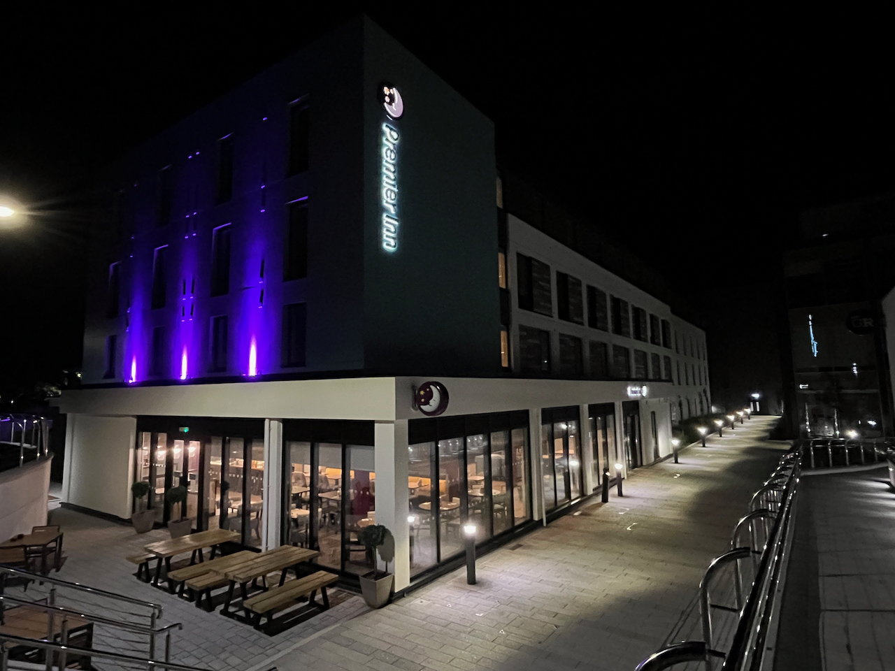 The Premier Inn in Guernsey at night. Glass windows around the bottom of the building reveal the restaurant inside.
