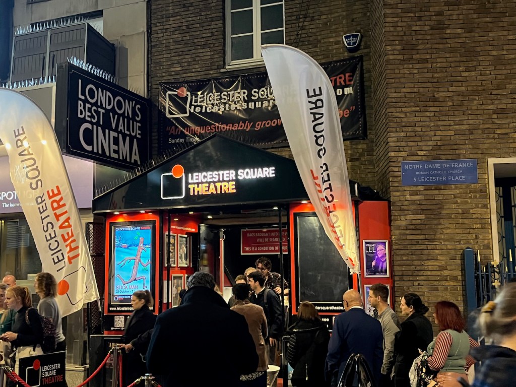 The entrance to the Leicester Square Theatre with a large crowd of people gathered outside.