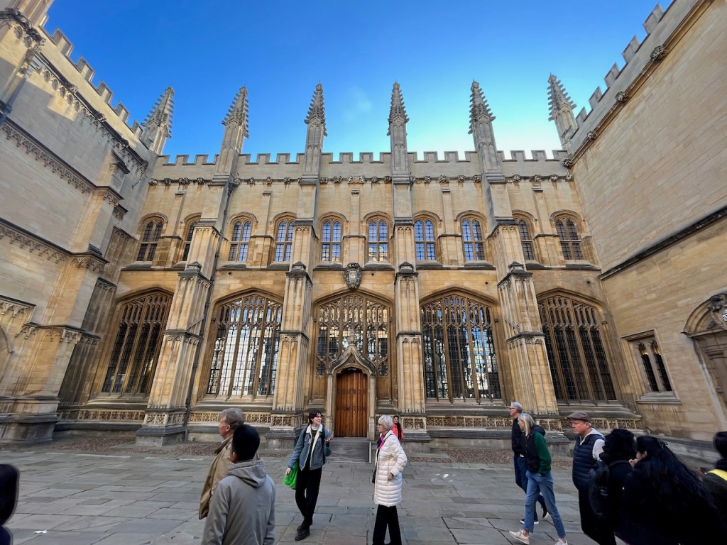 The Divinity School building in Oxford, a large, wide, ornate building with tall decorative spires across the top.