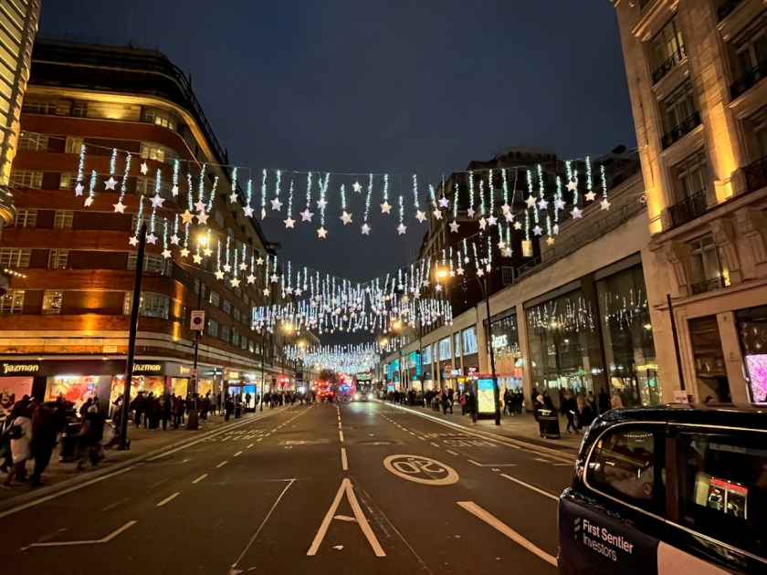 Bright stars dangling on illuminated threads of varying lengths, hanging from thin cables over Oxford Street, either straight across the road, or at diagonals so that cables overlap with each other.