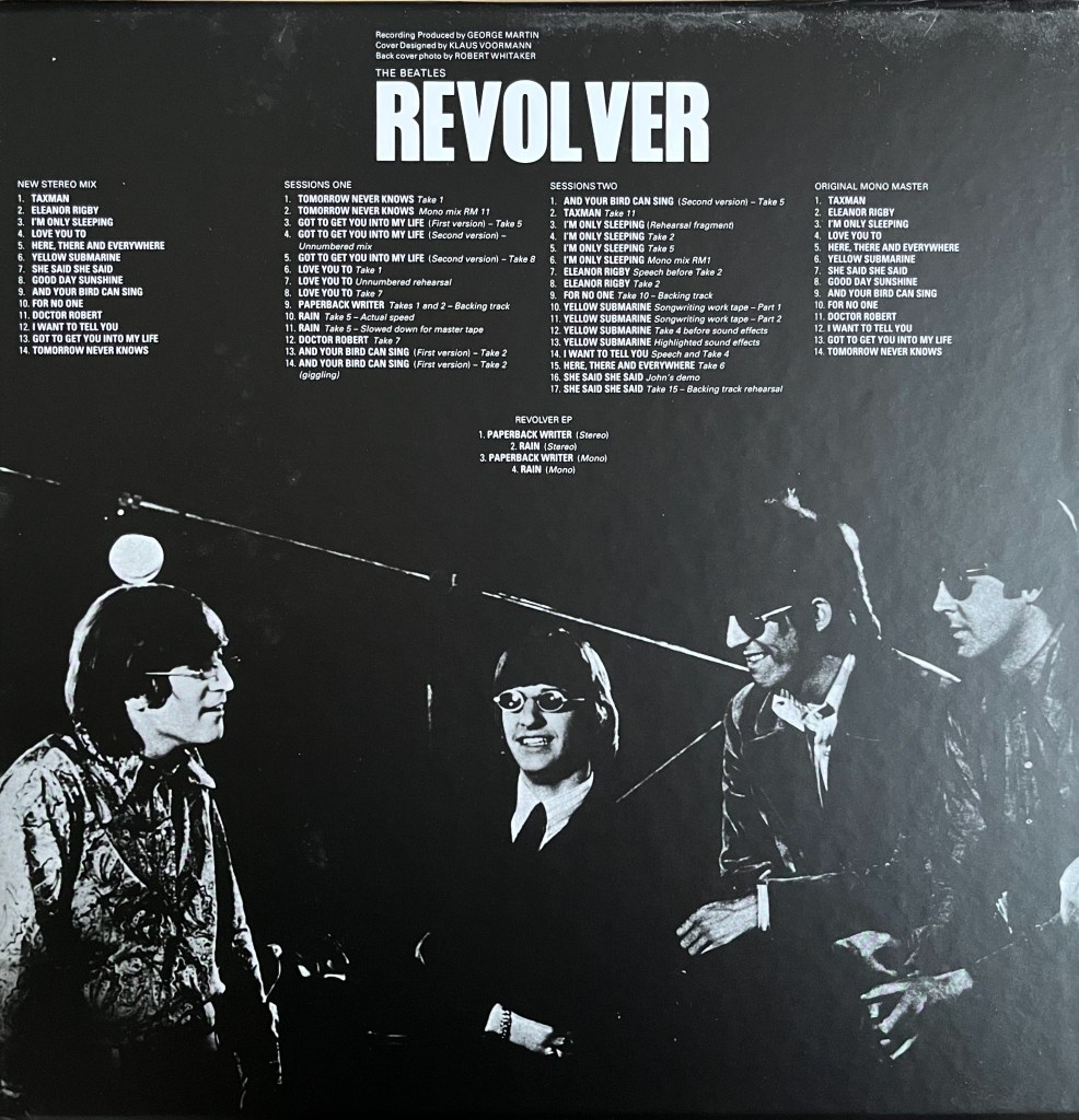 Back cover of the super deluxe box set for the album Revolver by The Beatles, with the track listings in white on a black background, above a black and white photo of the band looking happy together.