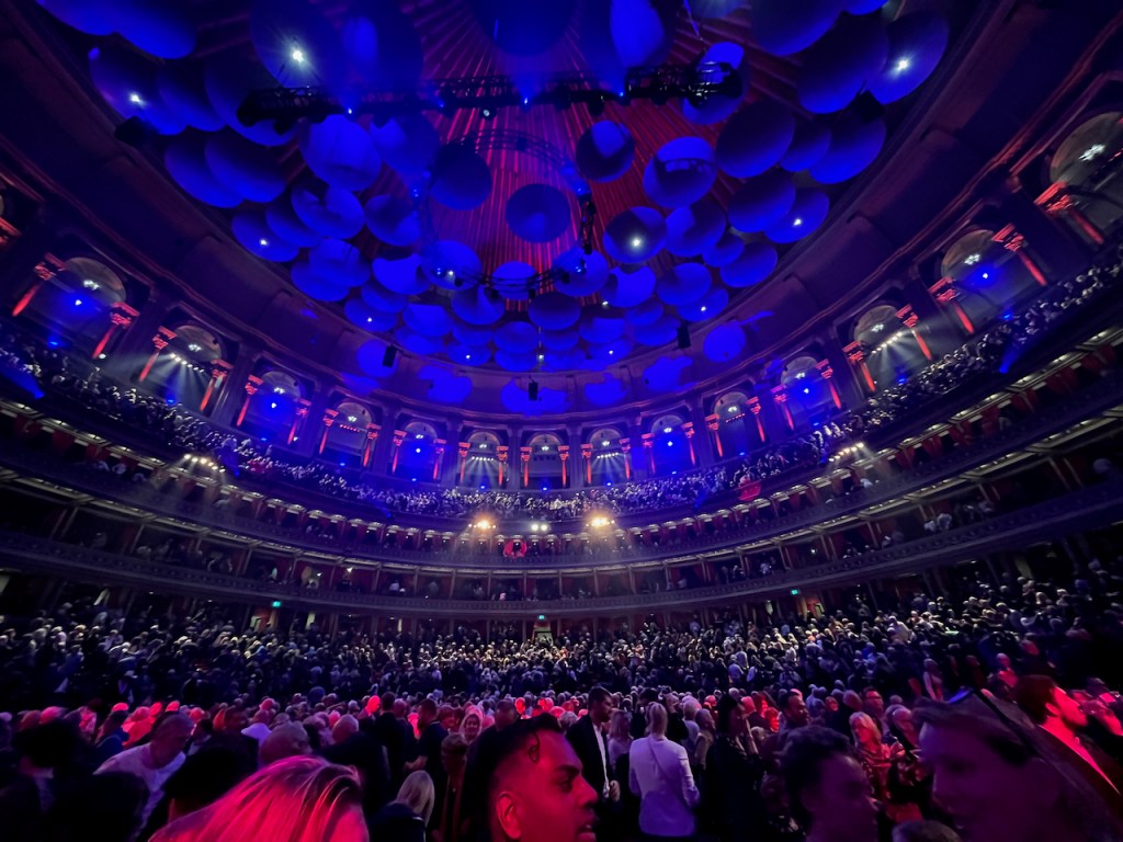 The huge circular auditorium of the Royal Albert Hall, filled with people.