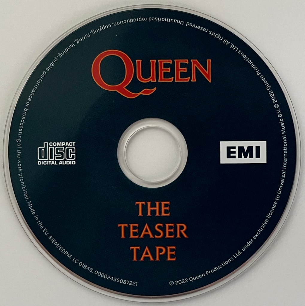 The mini CD teaser tape of The Miracle. Against a dark blue background, the Queen logo above the central hole is in red text with thin yellow edging, while the words The Teaser Tape below the centre are in yellow letters with thin red edging. In white, to the left and right of the centre respectively, are the Compact Disc Digital Audio and EMI logos.