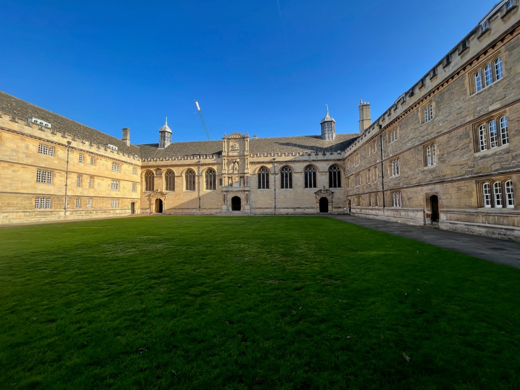 The large quad at Wadham College, a large square area of grass with a path around the outside, surrounded on all sides by a 3 storey building.