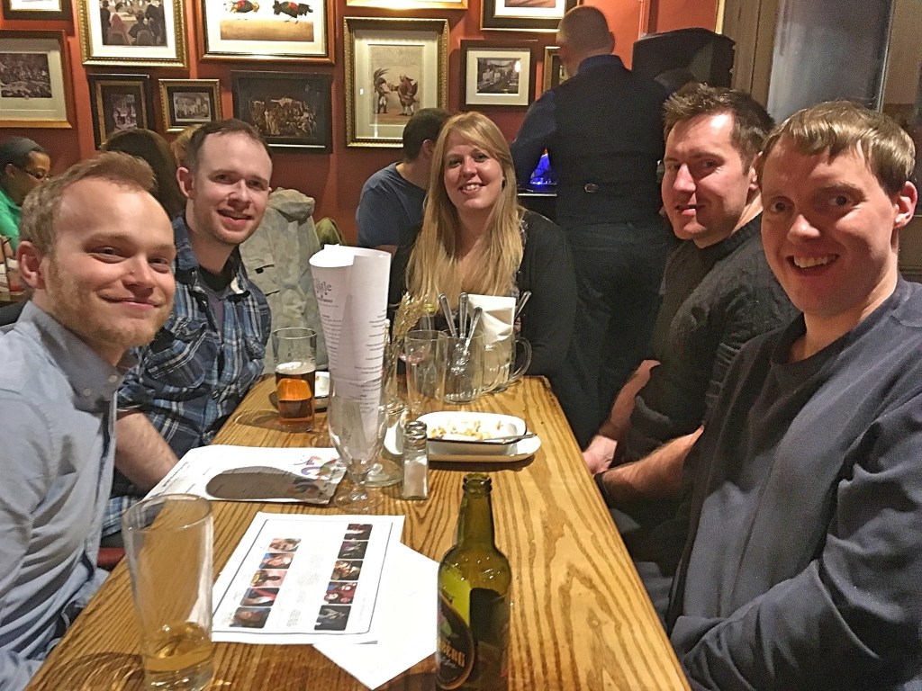 Glen with 3 other guys and 1 woman, all smiling while sat around a table in a pub, on which there are answer sheets to fill in for the Big Bob Quiz Of The Year, as well as their drinks.