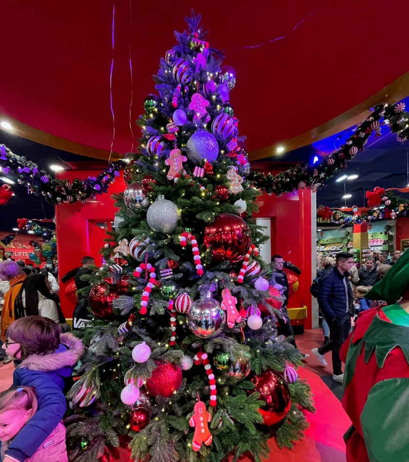 A large Christmas tree in Hamleys toy store, decorated with a variety of red, white and silver baubles, red and white striped candy canes, gingerbread men and lights.