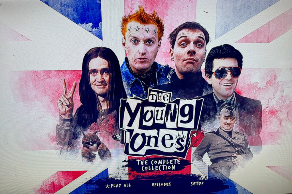 Blu-ray menu for The Young Ones, showing the main characters from the show around the title, all in front of a Union Jack background.