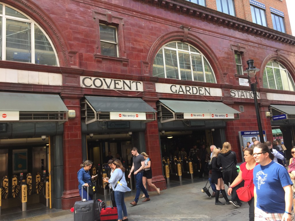 Covent Garden Tube Station, a large building with red tiled walls, and semi-circular windows above the ground floor.