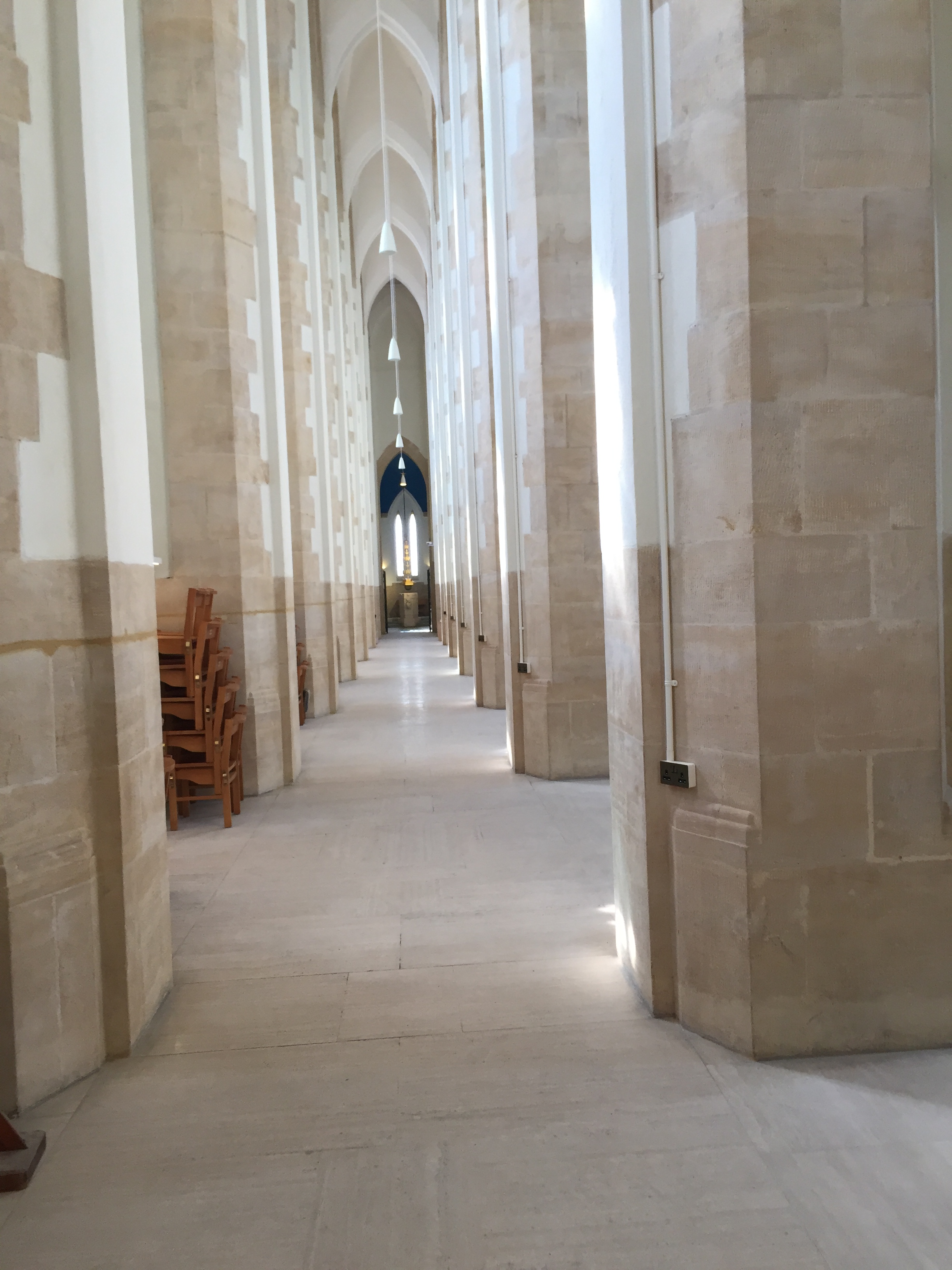 A narrow passageway lined by tall pillars in Guildford Cathedral.